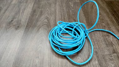 Açık mavi bir internet kablosu ahşap desenli zemine yerleştirilir..