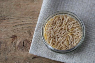 Raw Orzo Pasta on Wooden Background clipart