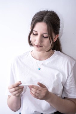 Beyaz gömlekli bir kız elinde beyaz bir gömlekle beyaz bir sandalyeye oturur ve çerçeveye bakar. konsept