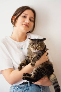 Kadın ve kedisi. Kollarında kedi tutan bir kadın..