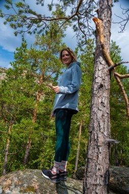 Yürüyüş ceketli bir kadın ve arka planda sırt çantası olan bir dağ manzarası..