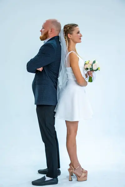 Gelin ve damat beyaz arka planda bir çiçekle stüdyoda