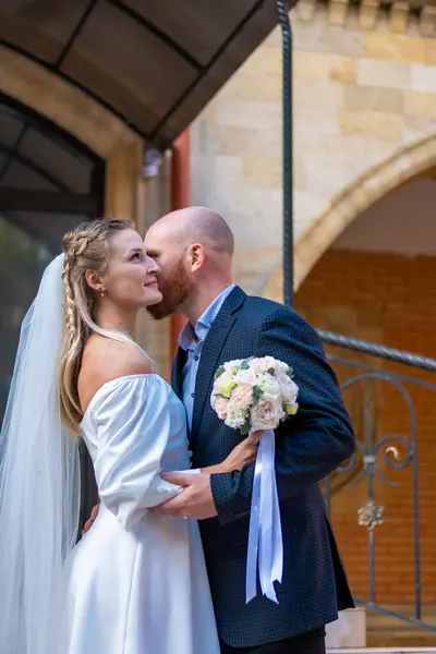 Mutlu gelin ve damat eski binanın arka planında öpüşüyorlar.