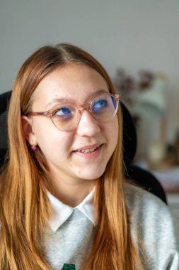 Gözlüklü ve gözlüklü genç kız dizüstü bilgisayarla masada oturuyor. Ofiste gözlüklü kız