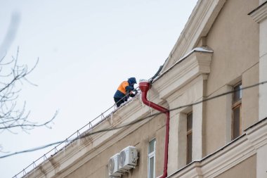 Binanın çatısını yapmak için elektrikli testereyle çalışan bir işçi.