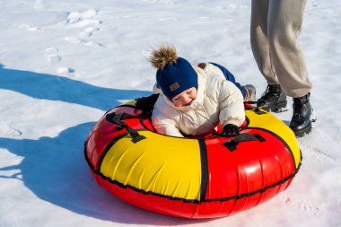 Kış parkında şişme topu olan küçük kız, mutlu çocuk karda eğleniyor.