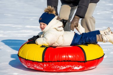 Kışlık giysiler içindeki küçük çocuk kafasında buzla şişme bir daire çiziyor.