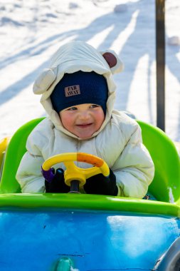 Küçük tatlı çocuk kızağa biniyor.