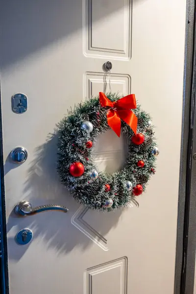 Kapı kolu olan bir Noel çelenginin dikey yakın çekimi.