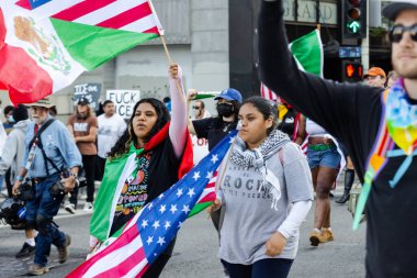 Muhtelif protestoculardan oluşan geniş bir kalabalık Los Angeles şehir merkezinde anti-ICE ve Trump karşıtı levhalarla Meksika ve Amerikan bayrakları sallayarak toplanıyor. Siyasi gösteri, göçmen hakları, sosyal adalet ve toplumsal dayanışmayı destekliyor. Fotoğraflı dur