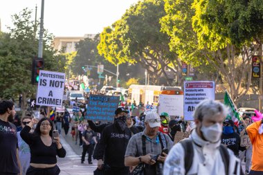 Muhtelif protestoculardan oluşan geniş bir kalabalık Los Angeles şehir merkezinde anti-ICE ve Trump karşıtı levhalarla Meksika ve Amerikan bayrakları sallayarak toplanıyor. Siyasi gösteri, göçmen hakları, sosyal adalet ve toplumsal dayanışmayı destekliyor. Fotoğraflı dur