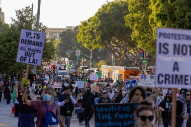 Muhtelif protestoculardan oluşan geniş bir kalabalık Los Angeles şehir merkezinde anti-ICE ve Trump karşıtı levhalarla Meksika ve Amerikan bayrakları sallayarak toplanıyor. Siyasi gösteri, göçmen hakları, sosyal adalet ve toplumsal dayanışmayı destekliyor. Fotoğraflı dur