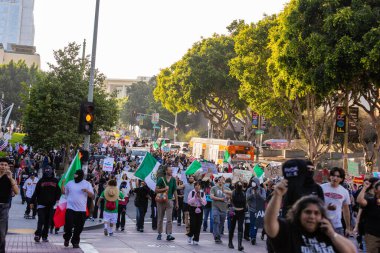 Muhtelif protestoculardan oluşan geniş bir kalabalık Los Angeles şehir merkezinde anti-ICE ve Trump karşıtı levhalarla Meksika ve Amerikan bayrakları sallayarak toplanıyor. Siyasi gösteri, göçmen hakları, sosyal adalet ve toplumsal dayanışmayı destekliyor. Fotoğraflı dur