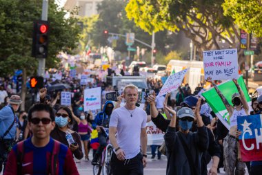 Muhtelif protestoculardan oluşan geniş bir kalabalık Los Angeles şehir merkezinde anti-ICE ve Trump karşıtı levhalarla Meksika ve Amerikan bayrakları sallayarak toplanıyor. Siyasi gösteri, göçmen hakları, sosyal adalet ve toplumsal dayanışmayı destekliyor. Fotoğraflı dur