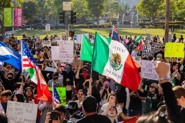 Muhtelif protestoculardan oluşan geniş bir kalabalık Los Angeles şehir merkezinde anti-ICE ve Trump karşıtı levhalarla Meksika ve Amerikan bayrakları sallayarak toplanıyor. Siyasi gösteri, göçmen hakları, sosyal adalet ve toplumsal dayanışmayı destekliyor. Fotoğraflı dur