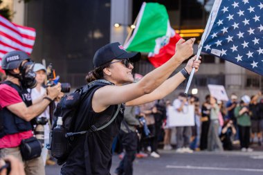 Muhtelif protestoculardan oluşan geniş bir kalabalık Los Angeles şehir merkezinde anti-ICE ve Trump karşıtı levhalarla Meksika ve Amerikan bayrakları sallayarak toplanıyor. Siyasi gösteri, göçmen hakları, sosyal adalet ve toplumsal dayanışmayı destekliyor. Fotoğraflı dur