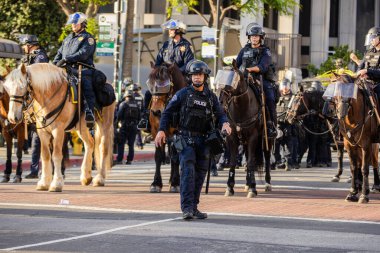 Muhtelif protestoculardan oluşan geniş bir kalabalık Los Angeles şehir merkezinde anti-ICE ve Trump karşıtı levhalarla Meksika ve Amerikan bayrakları sallayarak toplanıyor. Siyasi gösteri, göçmen hakları, sosyal adalet ve toplumsal dayanışmayı destekliyor. Fotoğraflı dur