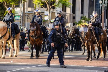 Muhtelif protestoculardan oluşan geniş bir kalabalık Los Angeles şehir merkezinde anti-ICE ve Trump karşıtı levhalarla Meksika ve Amerikan bayrakları sallayarak toplanıyor. Siyasi gösteri, göçmen hakları, sosyal adalet ve toplumsal dayanışmayı destekliyor. Fotoğraflı dur