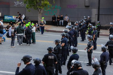 Muhtelif protestoculardan oluşan geniş bir kalabalık Los Angeles şehir merkezinde anti-ICE ve Trump karşıtı levhalarla Meksika ve Amerikan bayrakları sallayarak toplanıyor. Siyasi gösteri, göçmen hakları, sosyal adalet ve toplumsal dayanışmayı destekliyor. Fotoğraflı dur