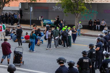 Muhtelif protestoculardan oluşan geniş bir kalabalık Los Angeles şehir merkezinde anti-ICE ve Trump karşıtı levhalarla Meksika ve Amerikan bayrakları sallayarak toplanıyor. Siyasi gösteri, göçmen hakları, sosyal adalet ve toplumsal dayanışmayı destekliyor. Fotoğraflı dur