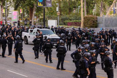 Muhtelif protestoculardan oluşan geniş bir kalabalık Los Angeles şehir merkezinde anti-ICE ve Trump karşıtı levhalarla Meksika ve Amerikan bayrakları sallayarak toplanıyor. Siyasi gösteri, göçmen hakları, sosyal adalet ve toplumsal dayanışmayı destekliyor. Fotoğraflı dur