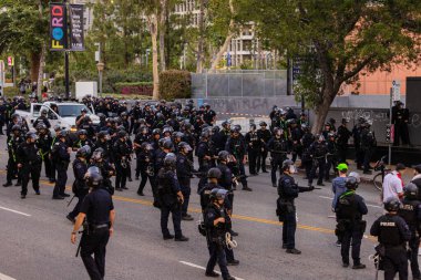 Muhtelif protestoculardan oluşan geniş bir kalabalık Los Angeles şehir merkezinde anti-ICE ve Trump karşıtı levhalarla Meksika ve Amerikan bayrakları sallayarak toplanıyor. Siyasi gösteri, göçmen hakları, sosyal adalet ve toplumsal dayanışmayı destekliyor. Fotoğraflı dur