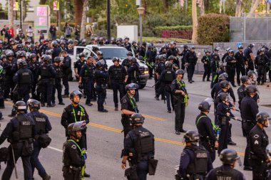 Muhtelif protestoculardan oluşan geniş bir kalabalık Los Angeles şehir merkezinde anti-ICE ve Trump karşıtı levhalarla Meksika ve Amerikan bayrakları sallayarak toplanıyor. Siyasi gösteri, göçmen hakları, sosyal adalet ve toplumsal dayanışmayı destekliyor. Fotoğraflı dur