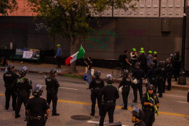Muhtelif protestoculardan oluşan geniş bir kalabalık Los Angeles şehir merkezinde anti-ICE ve Trump karşıtı levhalarla Meksika ve Amerikan bayrakları sallayarak toplanıyor. Siyasi gösteri, göçmen hakları, sosyal adalet ve toplumsal dayanışmayı destekliyor. Fotoğraflı dur