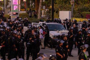 Muhtelif protestoculardan oluşan geniş bir kalabalık Los Angeles şehir merkezinde anti-ICE ve Trump karşıtı levhalarla Meksika ve Amerikan bayrakları sallayarak toplanıyor. Siyasi gösteri, göçmen hakları, sosyal adalet ve toplumsal dayanışmayı destekliyor. Fotoğraflı dur