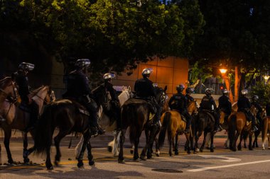Muhtelif protestoculardan oluşan geniş bir kalabalık Los Angeles şehir merkezinde anti-ICE ve Trump karşıtı levhalarla Meksika ve Amerikan bayrakları sallayarak toplanıyor. Siyasi gösteri, göçmen hakları, sosyal adalet ve toplumsal dayanışmayı destekliyor. Fotoğraflı dur