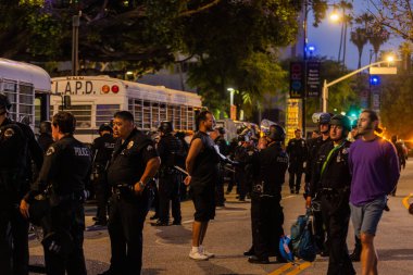 Muhtelif protestoculardan oluşan geniş bir kalabalık Los Angeles şehir merkezinde anti-ICE ve Trump karşıtı levhalarla Meksika ve Amerikan bayrakları sallayarak toplanıyor. Siyasi gösteri, göçmen hakları, sosyal adalet ve toplumsal dayanışmayı destekliyor. Fotoğraflı dur