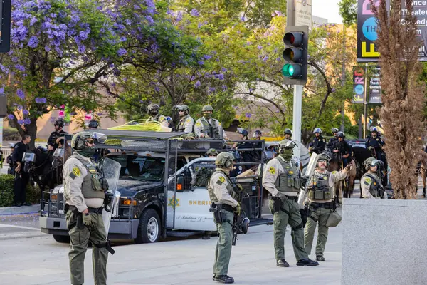 Muhtelif protestoculardan oluşan geniş bir kalabalık Los Angeles şehir merkezinde anti-ICE ve Trump karşıtı levhalarla Meksika ve Amerikan bayrakları sallayarak toplanıyor. Siyasi gösteri, göçmen hakları, sosyal adalet ve toplumsal dayanışmayı destekliyor. Fotoğraflı dur