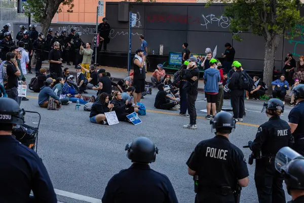 Muhtelif protestoculardan oluşan geniş bir kalabalık Los Angeles şehir merkezinde anti-ICE ve Trump karşıtı levhalarla Meksika ve Amerikan bayrakları sallayarak toplanıyor. Siyasi gösteri, göçmen hakları, sosyal adalet ve toplumsal dayanışmayı destekliyor. Fotoğraflı dur