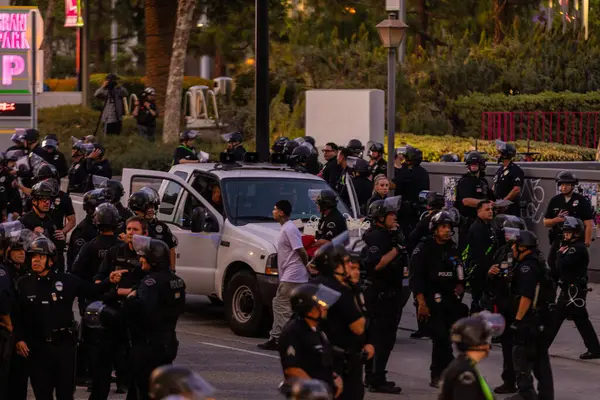 Muhtelif protestoculardan oluşan geniş bir kalabalık Los Angeles şehir merkezinde anti-ICE ve Trump karşıtı levhalarla Meksika ve Amerikan bayrakları sallayarak toplanıyor. Siyasi gösteri, göçmen hakları, sosyal adalet ve toplumsal dayanışmayı destekliyor. Fotoğraflı dur