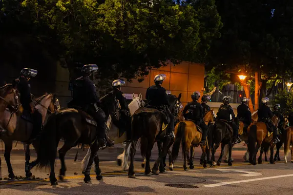 Muhtelif protestoculardan oluşan geniş bir kalabalık Los Angeles şehir merkezinde anti-ICE ve Trump karşıtı levhalarla Meksika ve Amerikan bayrakları sallayarak toplanıyor. Siyasi gösteri, göçmen hakları, sosyal adalet ve toplumsal dayanışmayı destekliyor. Fotoğraflı dur