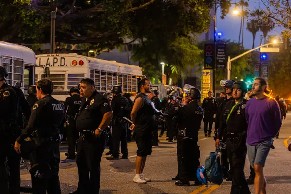 Muhtelif protestoculardan oluşan geniş bir kalabalık Los Angeles şehir merkezinde anti-ICE ve Trump karşıtı levhalarla Meksika ve Amerikan bayrakları sallayarak toplanıyor. Siyasi gösteri, göçmen hakları, sosyal adalet ve toplumsal dayanışmayı destekliyor. Fotoğraflı dur