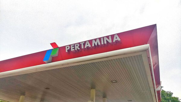 Kediri, East Java. Indonesia - December 02, 2023. Pertamina logo board at gas station with white cloud sky during the day.