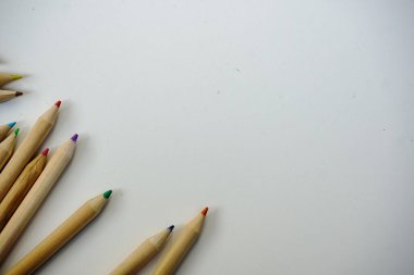 Açık gri arka planda toplu olarak dizilmiş ahşap renkli kalemler. Seçici odak