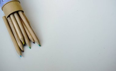 Açık gri arka planda toplu olarak dizilmiş ahşap renkli kalemler. Seçici odak