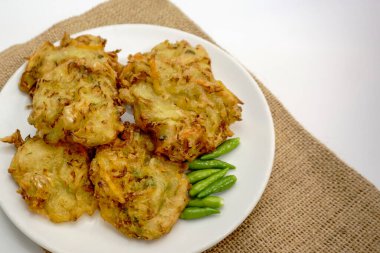 Selective focus Bakwan sayur or Bakwan Goreng or bala-bala or ote-ote is vegetebles fritter from Indonesia, served with cayenne peppers on white plate. clipart
