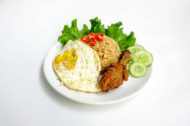 Kızarmış pirinç, tavuk ve sebzeler beyaz tabakta. Nasi Goreng - Endonezya usulü kızarmış tavuklu pilav beyaz tabakta izole edilmiş. Nasi Goreng bir Endonezya mutfağı. Bali yemeği. Asya yemeği. Üst görünüm