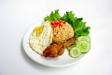 Kızarmış pirinç, tavuk ve sebzeler beyaz tabakta. Nasi Goreng - Endonezya usulü kızarmış tavuklu pilav beyaz tabakta izole edilmiş. Nasi Goreng bir Endonezya mutfağı. Bali yemeği. Asya yemeği. Üst görünüm