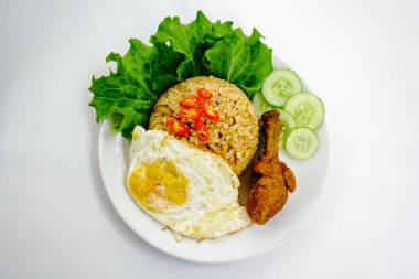 Kızarmış pirinç, tavuk ve sebzeler beyaz tabakta. Nasi Goreng - Endonezya usulü kızarmış tavuklu pilav beyaz tabakta izole edilmiş. Nasi Goreng bir Endonezya mutfağı. Bali yemeği. Asya yemeği. Üst görünüm