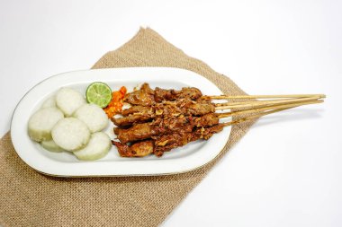 Fıstık soslu Sate Ayam (Tavuk satay) ve lontong (pirinç keki). Endonezya 'nın popüler sokak yemeklerinden biri. Beyaz masada beyaz tabakta servis ediliyor. Seçici odak.