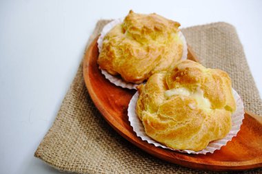 Choux pastasının seçici odak noktası. Ev yapımı choux keki ya da kremalı pasta ya da vanilyalı kremalı ekler. Fransız tatlısı. Beyaz arkaplan ile gürültülü görünüyor.
