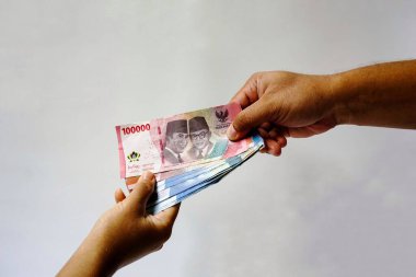 Rupiah parasını tutan adamın eli beyaz arka planda izole edilir. Para vermek ve almak. Finans, ödeme, maaş konsepti
