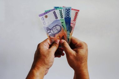 Rupiah parasını tutan adamın eli beyaz arka planda izole edilir. Para vermek. Finans, ödeme, maaş konsepti