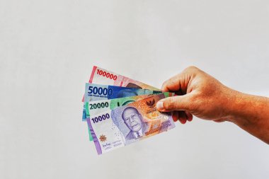 Rupiah parasını tutan adamın eli beyaz arka planda izole edilir. Para vermek. Finans, ödeme, maaş konsepti