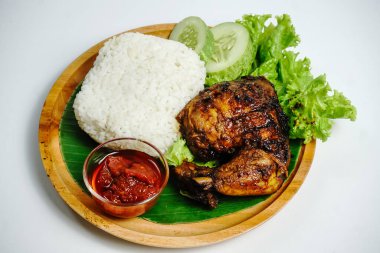 Izgara tavuk, pilav, biber ezmesi, bir dilim salatalık ve marul yaprağı ile servis edilir. Nasi ayam bakar lalapan, Endonezya ızgara tavuğunun otantik tarifi..