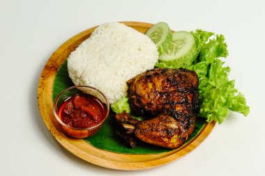 Izgara tavuk, pilav, biber ezmesi, bir dilim salatalık ve marul yaprağı ile servis edilir. Nasi ayam bakar lalapan, Endonezya ızgara tavuğunun otantik tarifi..